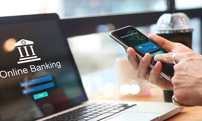 A customer logs onto a banking app on their laptop while also using a phone.