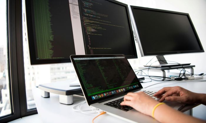 Hands on a keyboard in front of monitors where a software QA pro tests an AI application