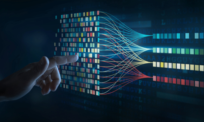 A person's hand with pointer finger pointing toward multicolored, complex data representation on a computer screen.