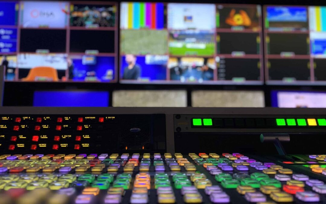 Rows of buttons in a TV media center in front of a wall of TV screens.