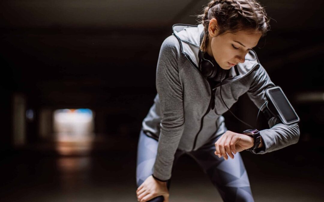 You ng woman who has just finished a workout checks her fitness tracker for metrics