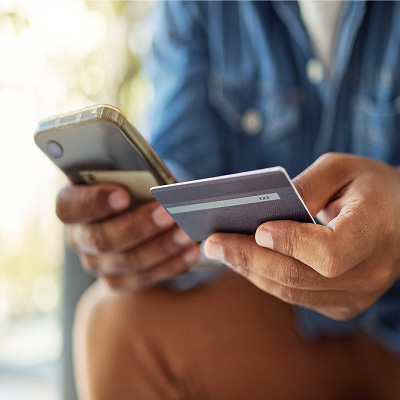 Person using a smartphone and credit card for mobile banking.