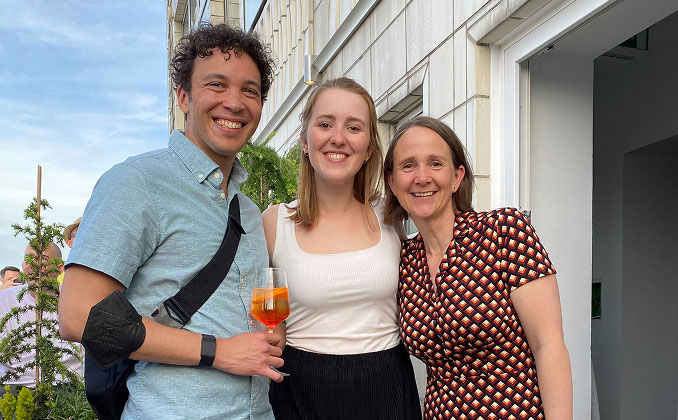 Three Applause colleagues smiling for a photo while holding drinks at an outdoor company social event.
