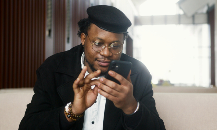 A man wearing a hat interacts with a smartphone.